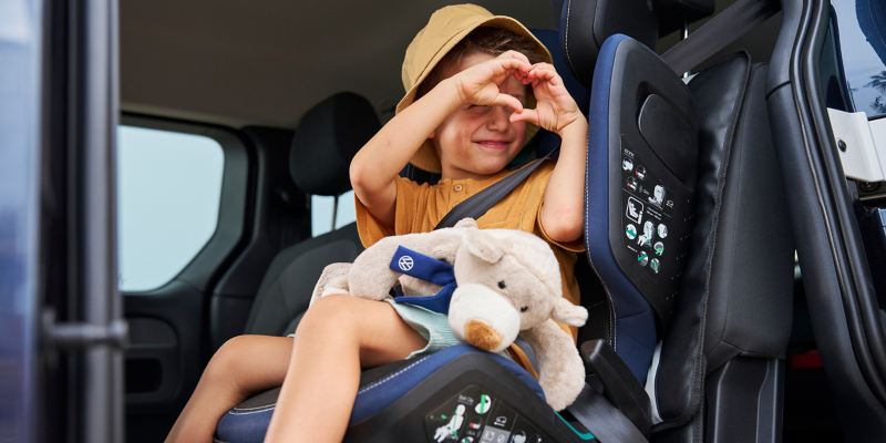 Boy in a VW Accessories child seat forms a heart with his hands