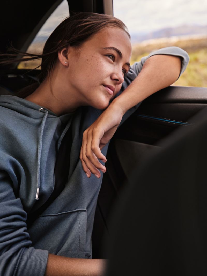 Jugendliche im VW Auto blickt verträumt durch das Fenster nach draußen