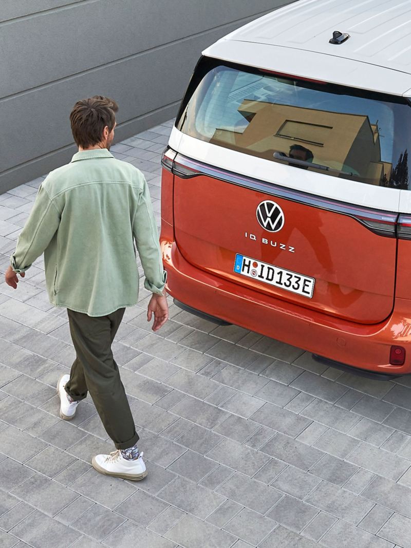 A man walks past the rear of his VW ID. Buzz