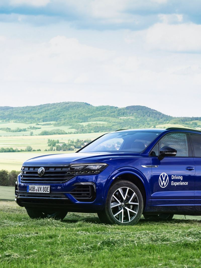A VW Touareg R in a field – a hilly landscape in the background