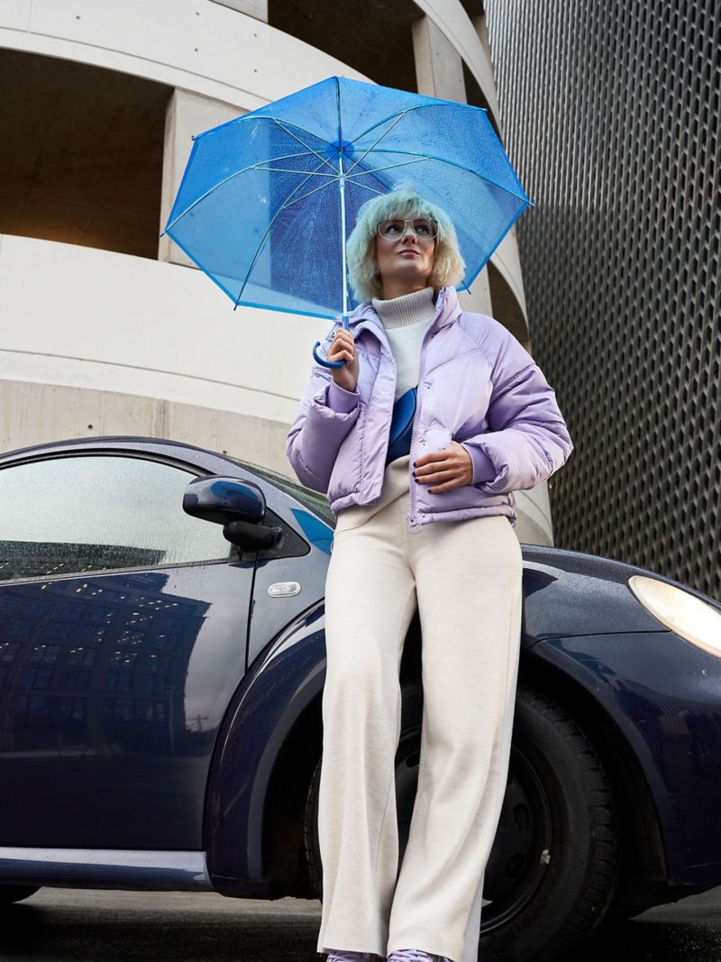 Une femme se tenant à côté de sa VW Nouvelle Coccinelle