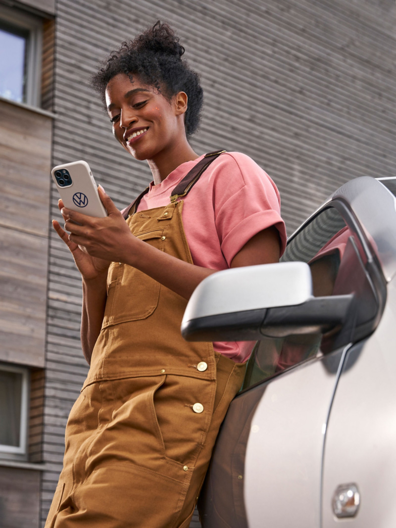 Kobieta opiera się o VW Polo 4 i patrzy na smartfon