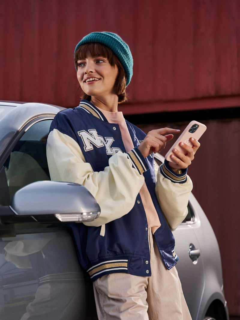 Une femme avec un smartphone appuyée contre une VW Polo 4