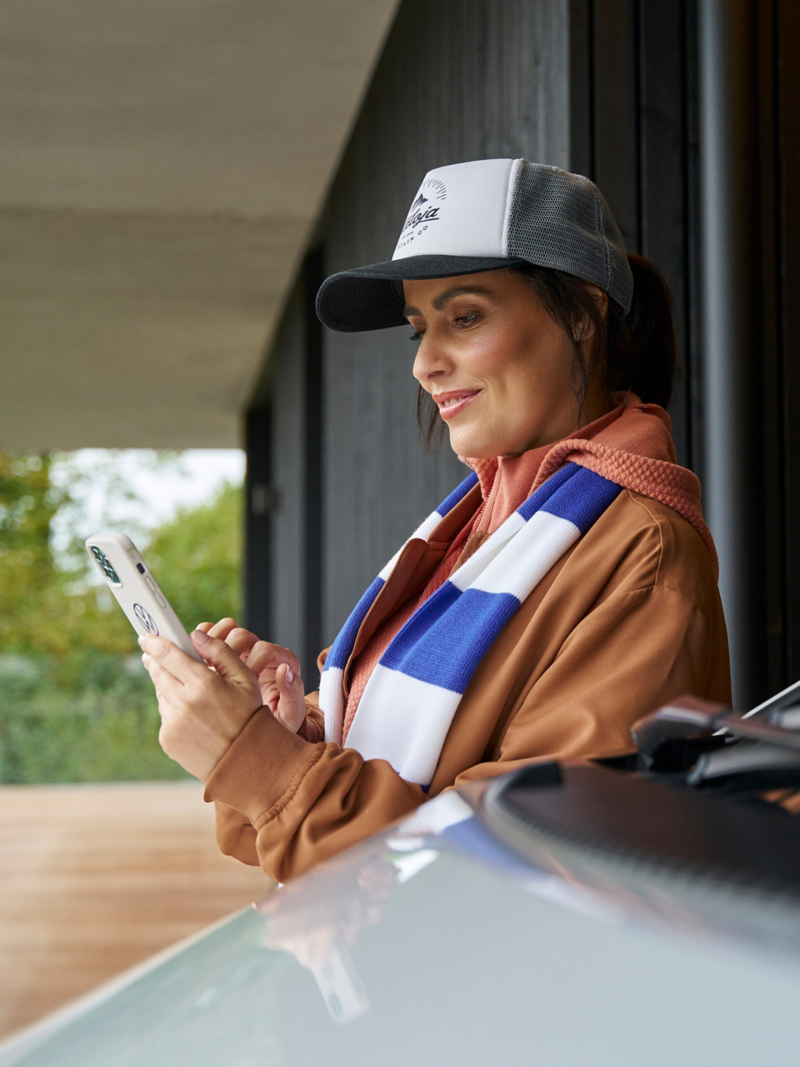 Woman with blue and white scarf operates her smartphone