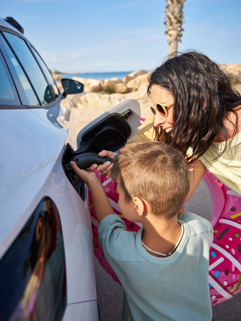 Μητέρα και γιος φορτίζουν ένα αυτοκίνητο VW ID. με καλώδιο φόρτισης από τη VW Accessories