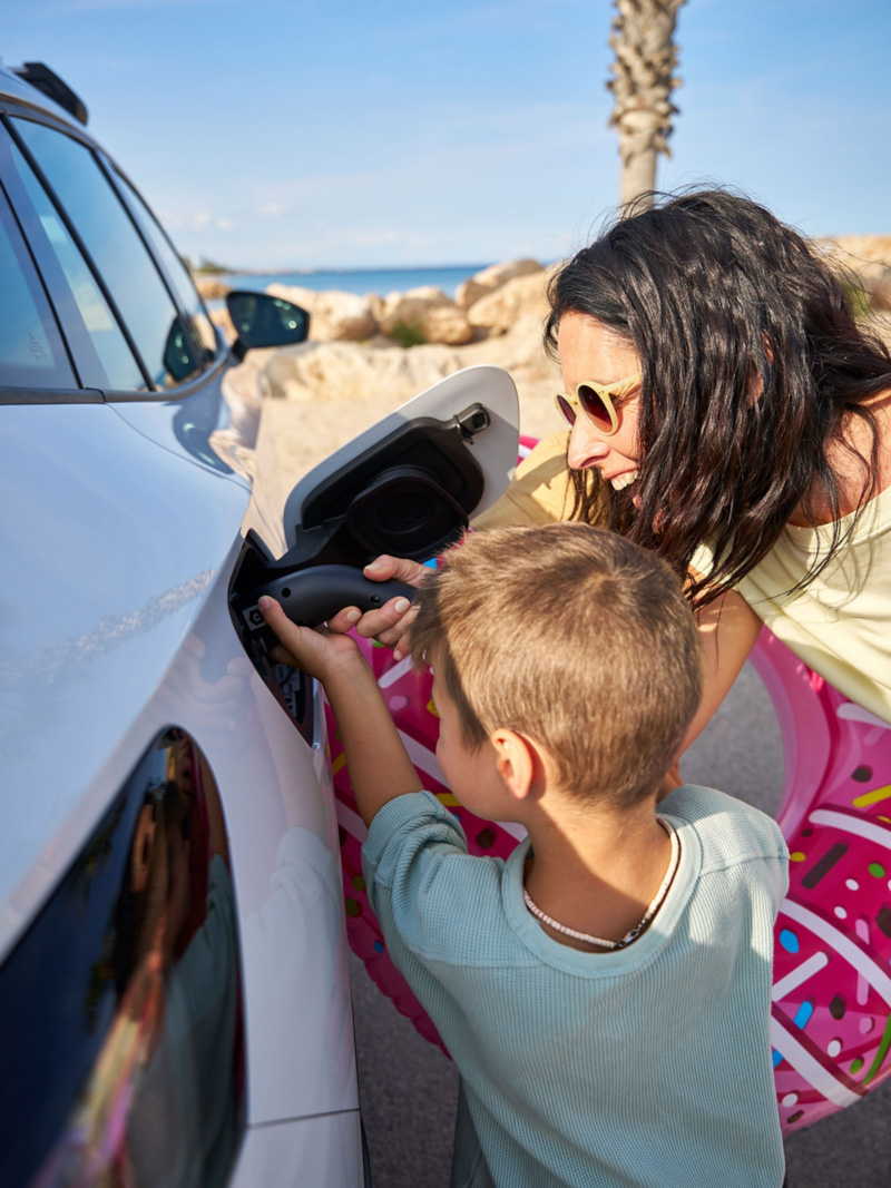 Matka i syn ładują samochód VW ID. za pomocą przewodu do ładowania z oferty Akcesoriów VW