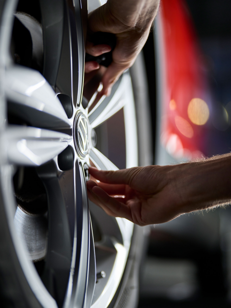 Iemand bevestigt een wielbout aan een VW-band