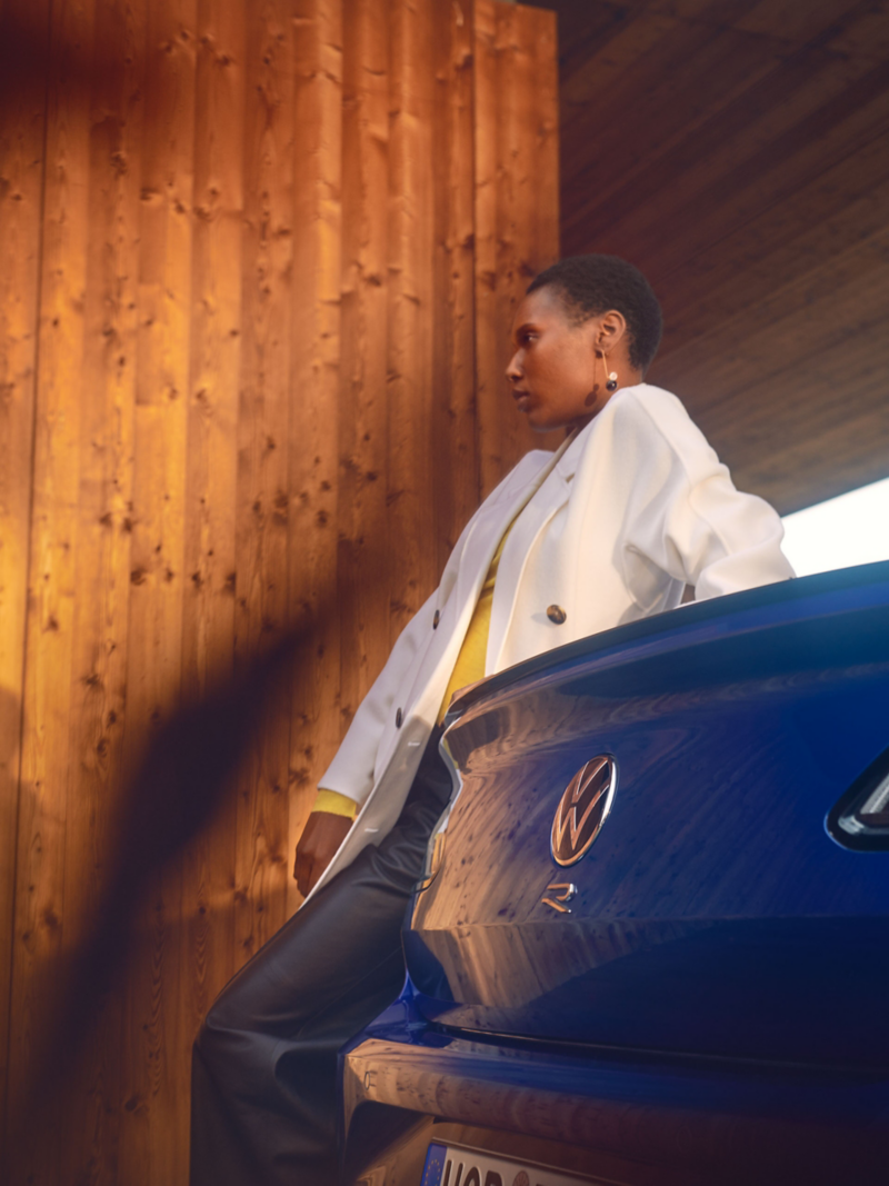 Kobieta opiera się o tył swojego Volkswagena Arteon R.