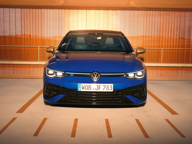 A woman stands next to her parked VW R Golf R