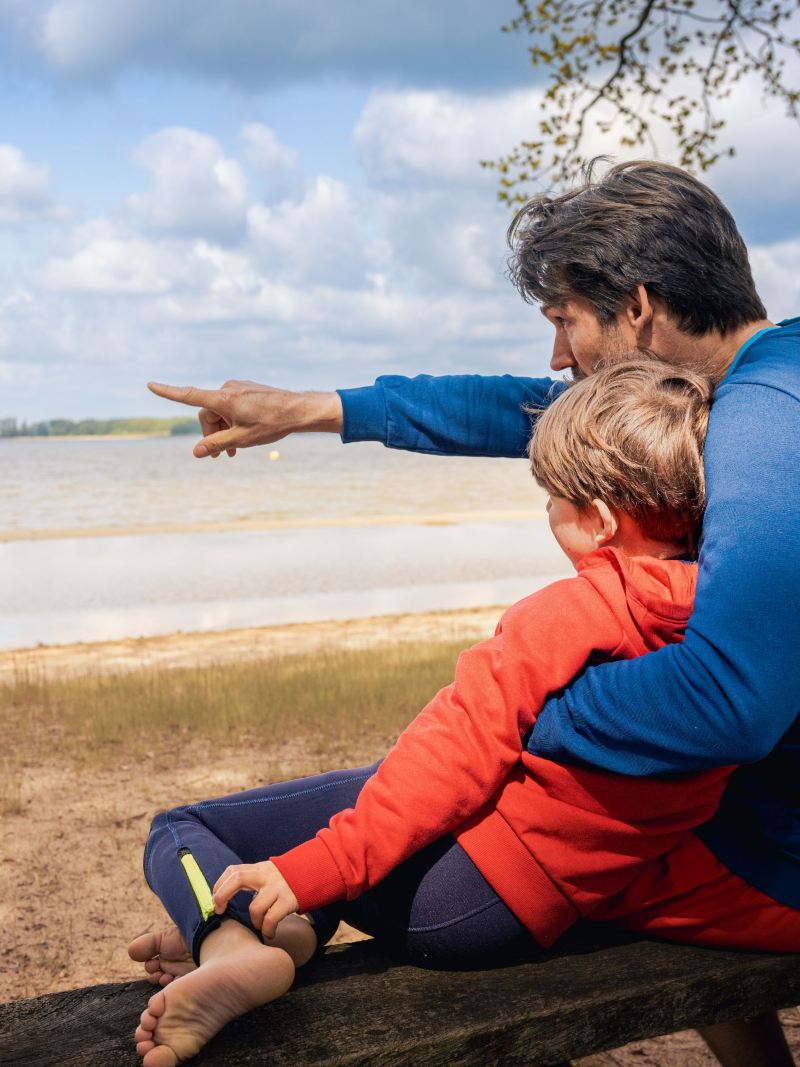 Ein Vater deutet auf den See, um seinem Sohn etwas zu zeigen