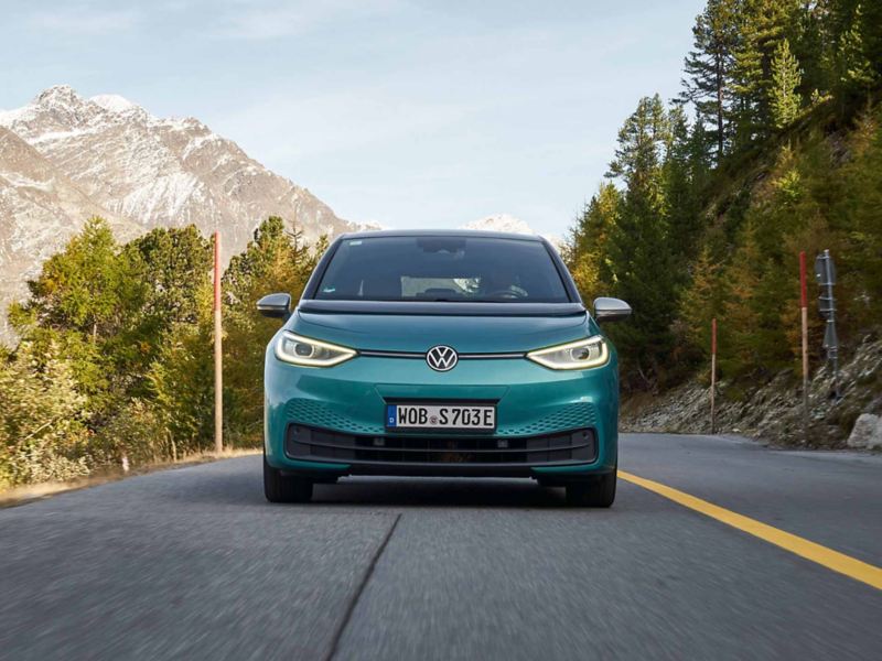 Ripresa frontale di una macchina Volkswagen e all'orizzonte un paesaggio di montagna.