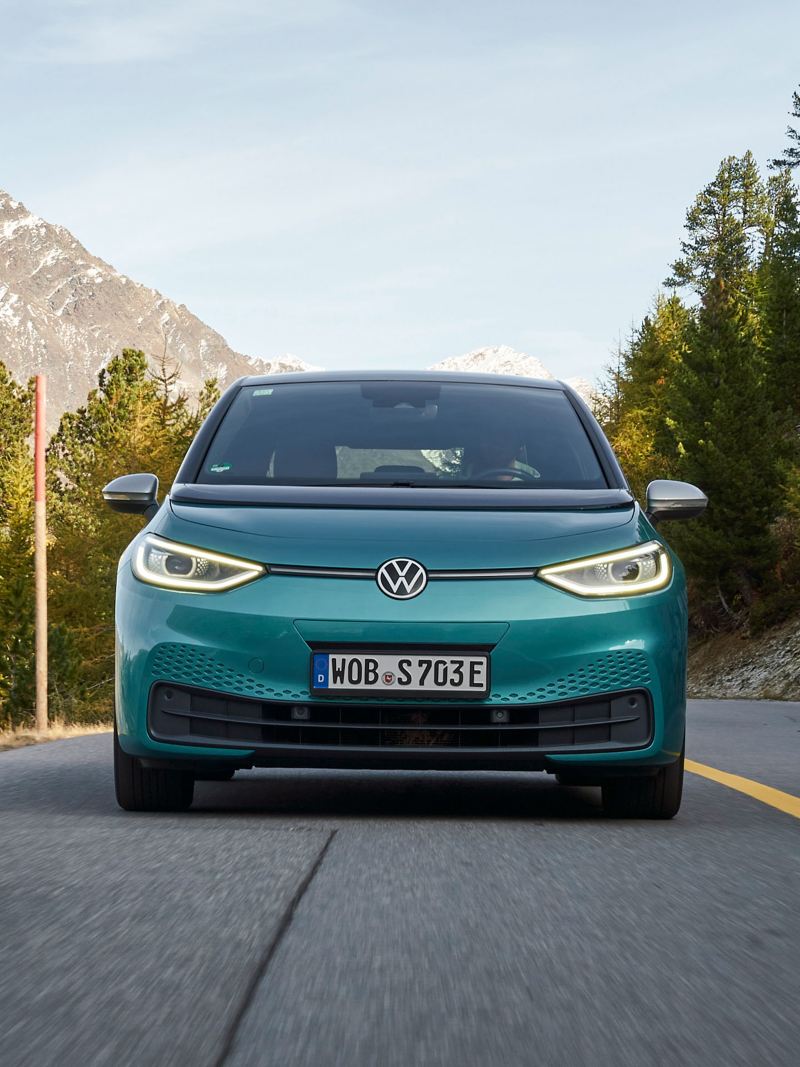 A VW ID.3 on a country road, mountains in the background