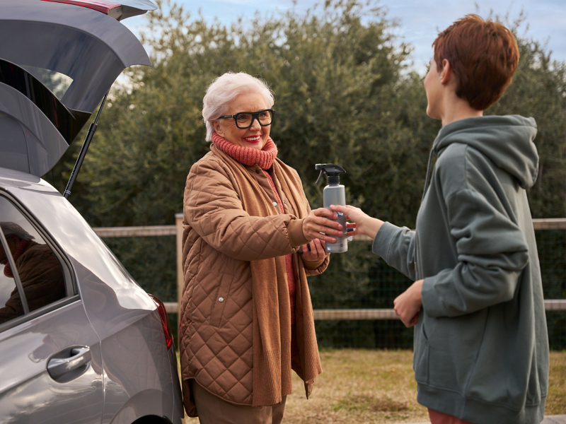 Una mujer entrega a otra una botella de productos de cuidado VW Accesorios