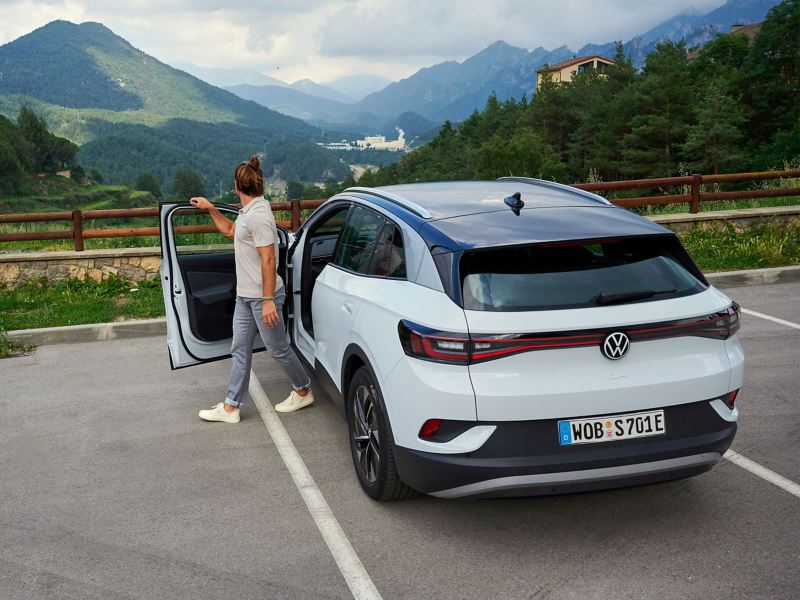 Un homme sort de la Volkswagen ID.4 et profite d’une vue idyllique sur des paysages de montagne