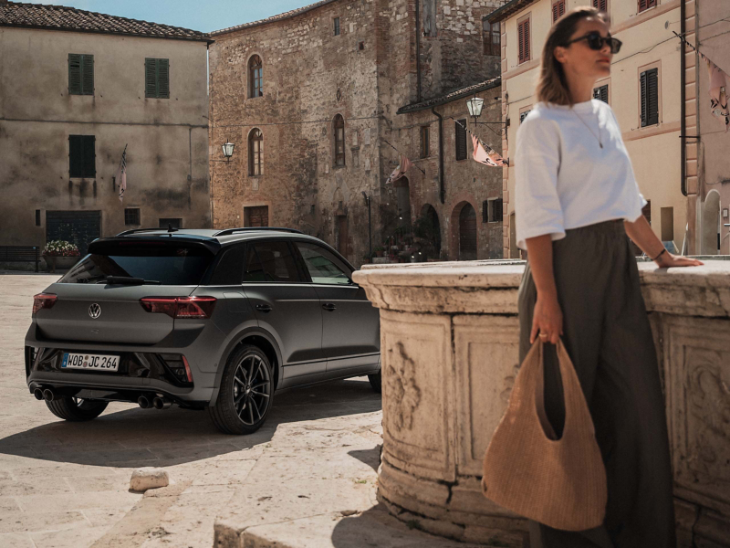 En VW T-Roc R sedd bakifrån med upplysta bromsljus. En kvinna går i förgrunden.