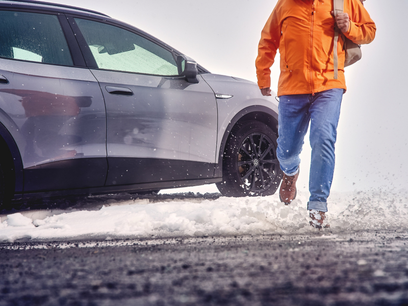 Uomo che si allontana da un VW ID.4 Pro parcheggiato nella neve.
