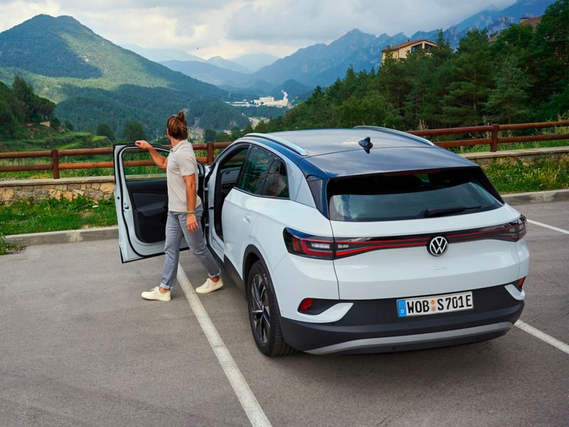 Man gets out of VW ID.4 and enjoys view of idyllic mountain scenery