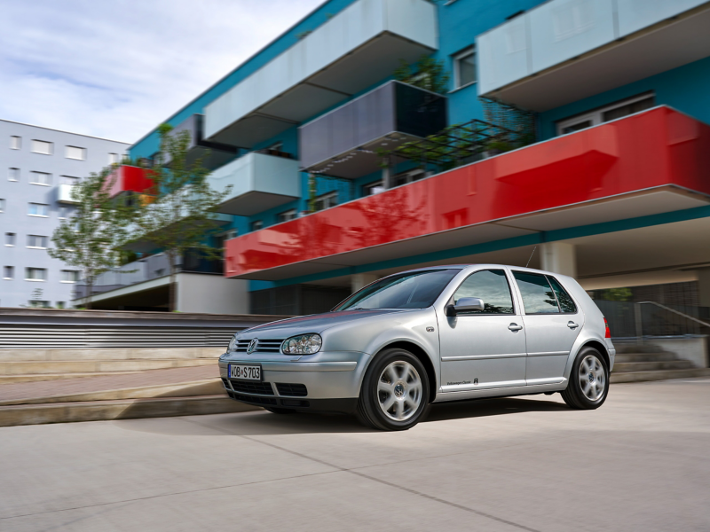 Un Volkswagen Golf 4 circulando al lado de un bloque de pisos