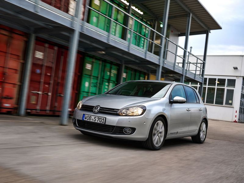 VW Golf 6 fährt an einem Containerlager vorbei