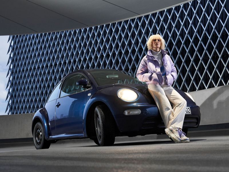 Eine Frau und ihr gebrauchter VW New Beetle der Kompaktklasse