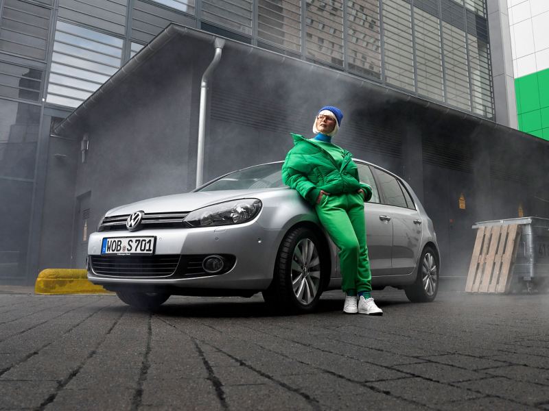A woman leans against her VW Golf 6
