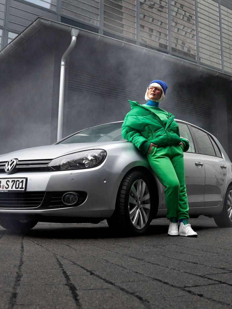 A woman leans against her VW Golf 6