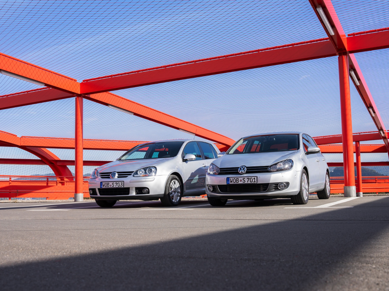 Two silver VW previous models on a car park deck