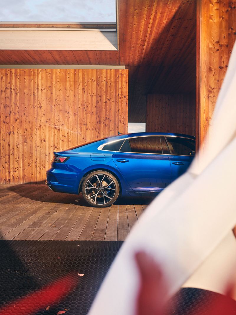 En blå VW Arteon R står parkerad i en carport.