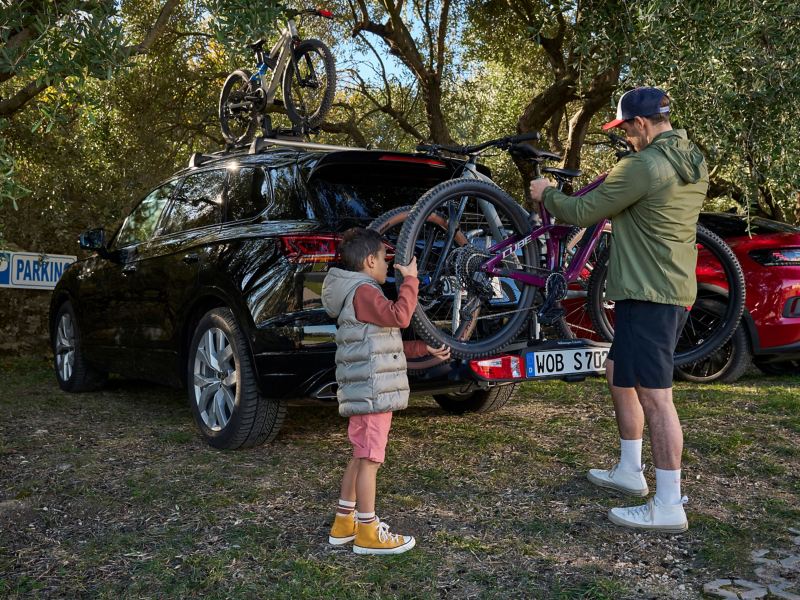 Un père et son fils retirent un vélo d’un porte-vélos des accessoires VW installé sur une VW Touareg