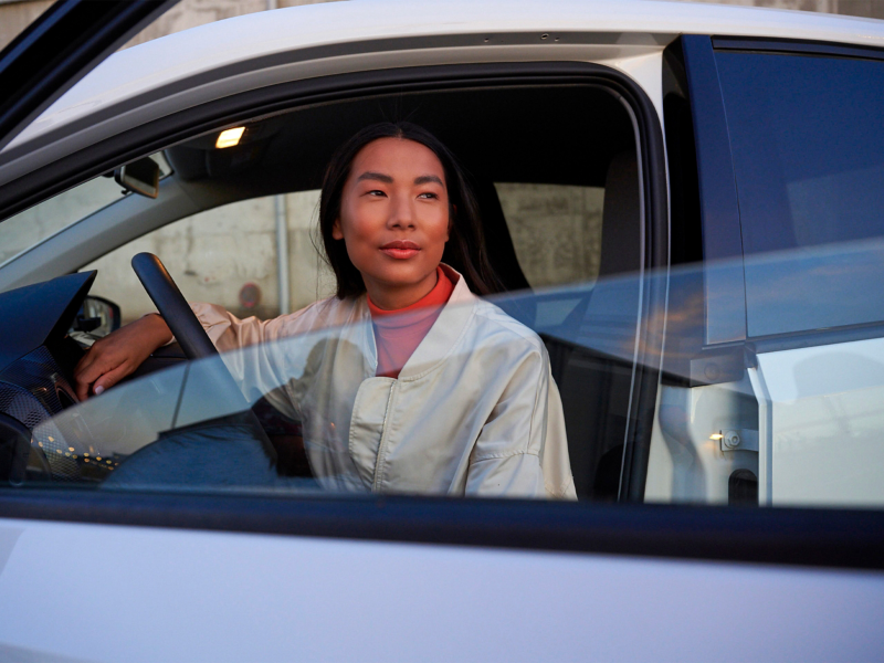 Woman looks out of VW up! with open driver’s door
