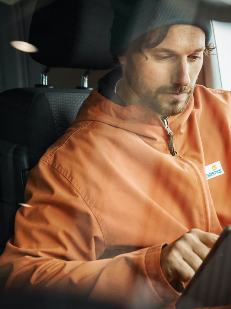 Mężczyzna siedzi w VW Transporter i obsługuje tablet.