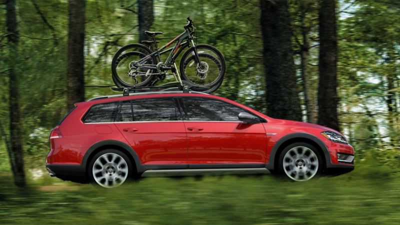 Red Golf Alltrack driving through forest with bikes 