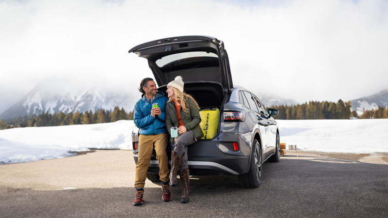 Un homme et une femme assis dans le coffre ouvert de la Volkswagen ID.4 2024
