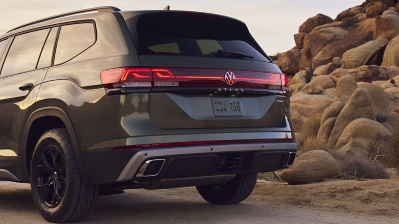 The rear view of the Avocado Green 2024 Volkswagen Atlas on the mountain road.