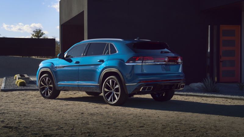 Vue arrière d’un Atlas Cross Sport 2024 de Volkswagen bleu stationné près d’une maison avec un hayon facile à ouvrir