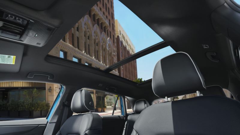 The interior of the 2024 Volkswagen Atlas Cross Sport featuring a panoramic sunroof and front seats