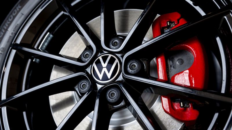 Gros plan sur la roue d’une Jetta GLI 2024. La roue est noire avec un logo Volkswagen argenté au centre. La roue a 10 rayons et un étrier de frein rouge.