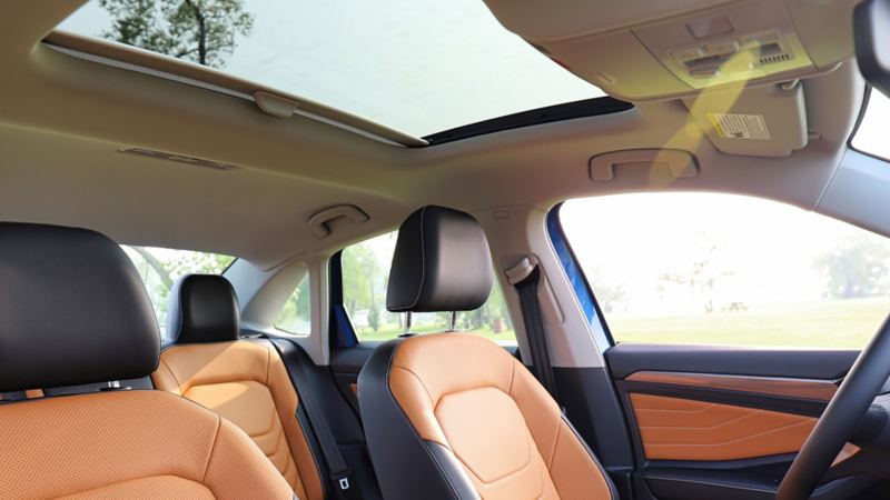 L’intérieur de la Jetta 2024 de Volkswagen. La voiture a des sièges en cuir orange avec des ornements noirs, un tableau de bord noir et une console centrale.