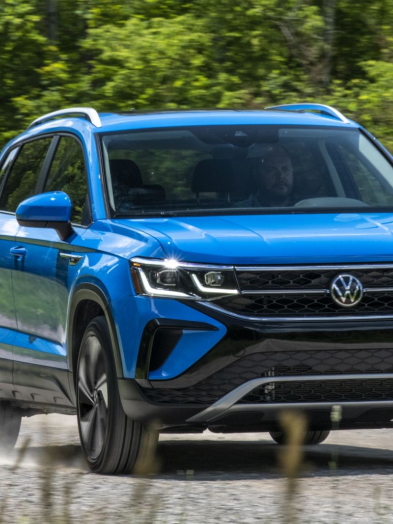 The blue 2024 Volkswagen Taos driving on the road