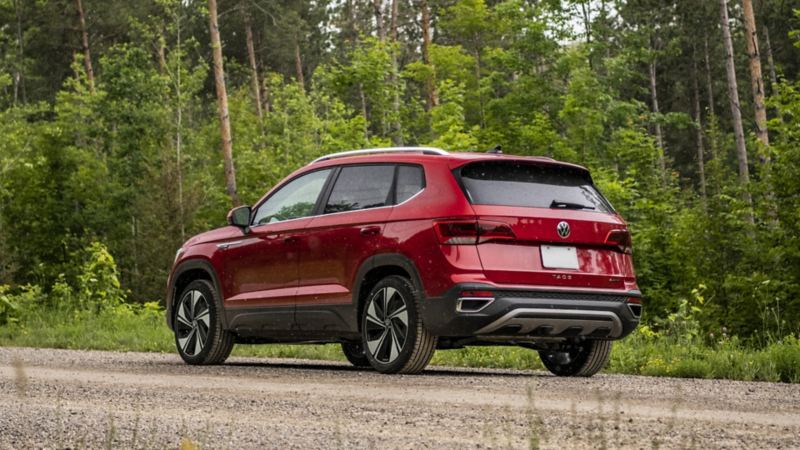 The red 2024 Volkswagen Taos with 4MOTION® All-Wheel Drive parked on a road near a forest