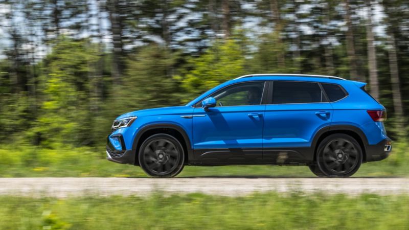 The blue 2024 Volkswagen Taos driving in a forest