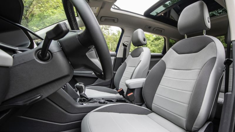 The interior of the 2024 Volkswagen Taos featuring front seats, sunroof and a steering wheel