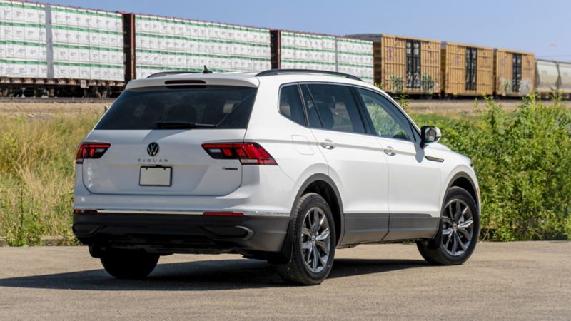 A rear-view photo of the white 2024 Volkswagen Tiguan parked near a railway road