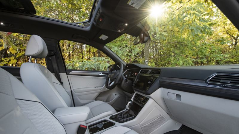 An interior view of the 2024 Volkswagen Tiguan featuring front seats, steering wheel and a sunroof 