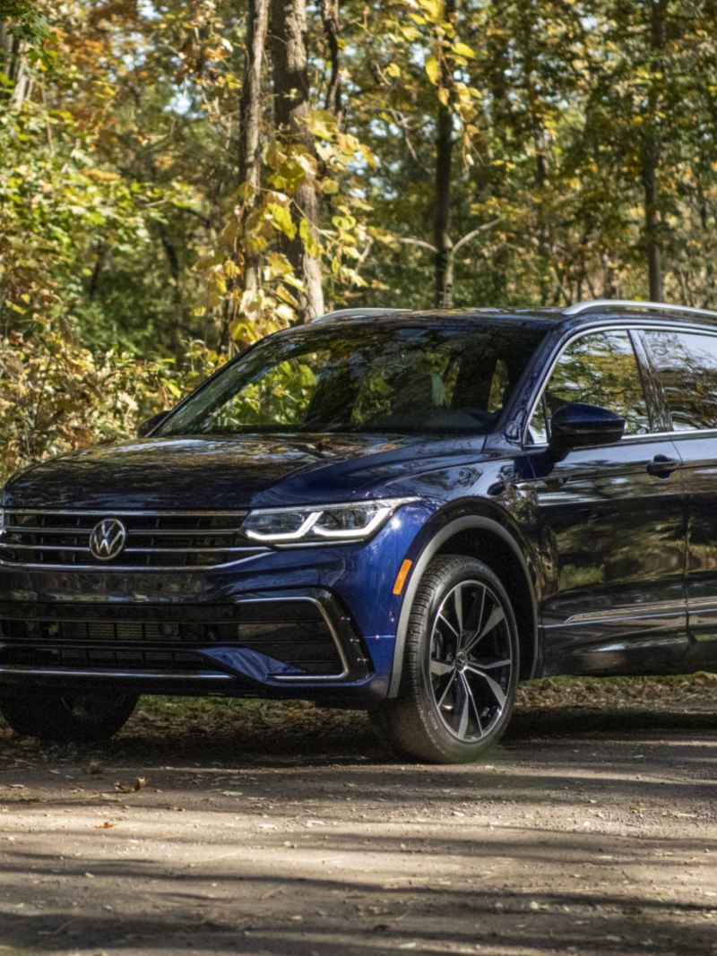 Un Tiguan 2024 bleu de Volkswagen est garé sur une route en forêt