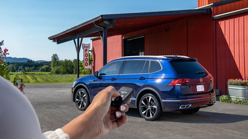 A hand of a man pushing a remote start button on the fob of the 2024 Volkswagen Tiguan