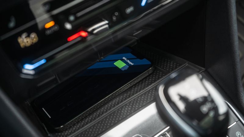 A close-up photo of the mobile phone charging on the wireless charging pod of the 2024 Volkswagen Tiguan