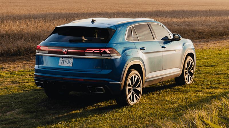 A blue Atlas Cross Sport 2025 parked on a grassy field during golden hour.