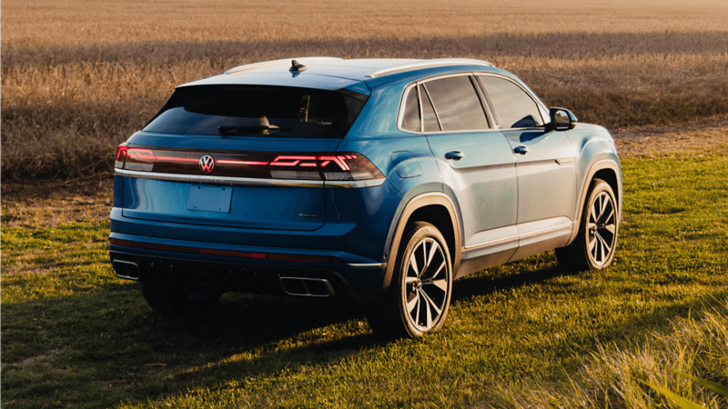 A blue Atlas Cross Sport 2025 parked on a grassy field during golden hour.