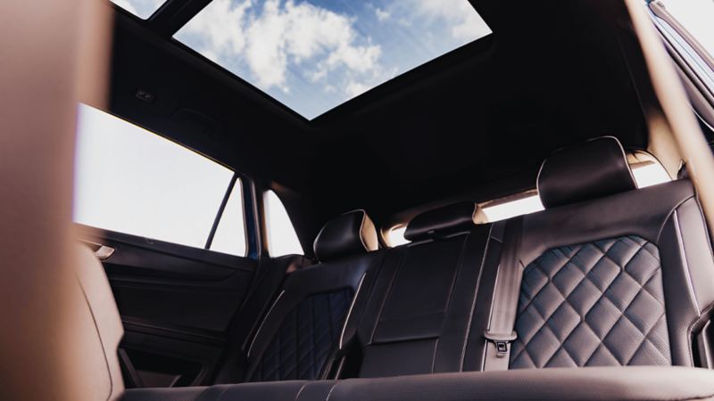 The Atlas Cross Sport interior with luxurious leather seats with diamond stitching and an open sunroof showing a clear blue sky.